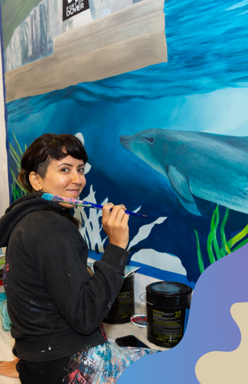 Woman painting a mural of a serene ocean scene